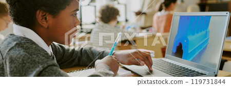 Student engaging in educational activities on laptop while holding pen, surrounded by classmates in classroom setting, enhancing learning experience using technology Student engaging in educational activities on laptop while holding pen, surrounded by classmates in classroom setting, enhancing learning experience using technology 119731844