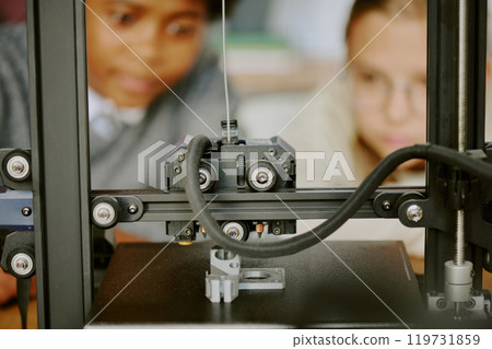 Students observing intricate 3D printing process with focused expressions, showcasing technology in educational environment 119731859