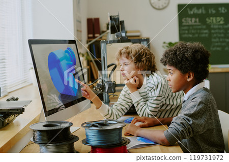 Children focusing on computer screen displaying 3D model in classroom setting with wires and gadgets on the desk, learning about 3D design technology 119731972