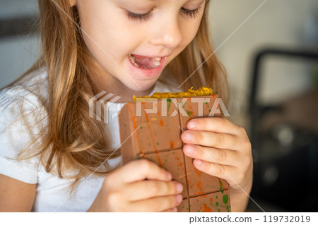 Little girl eating Dubai chocolate with pistachio paste and kataifi dough. Confectionery handmade sweets at home in the kitchen.  119732019