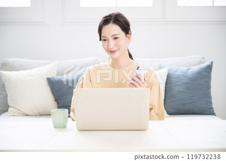 Close-up of a woman holding a smartphone, working on a computer, searching or researching, looking at the screen 119732238