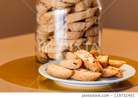 Almond cantucci biscuits on plate with jar behind showcasing traditional recipe Almond cantucci biscuits on plate with jar behind showcasing traditional recipe 119732401