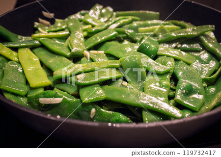 Sauteed flat beans with garlic spices in pan vibrant green beans cooking in oil Italian side 119732417
