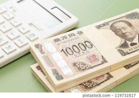 A stack of 10,000 yen bills and a calculator on a green background 119732817