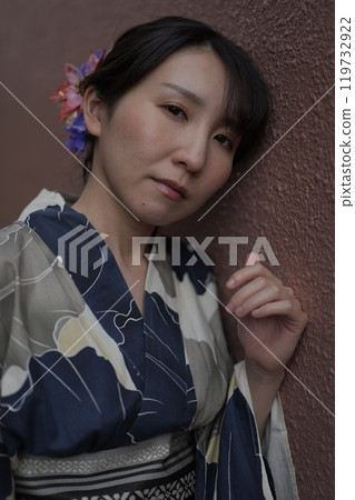A young woman in a yukata standing against a brown wall A young woman in a yukata standing against a brown wall 119732922