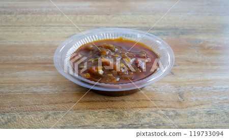 Sambal is Indonesian chili sauce made from peppers, shrimp paste, garlic, ginger, shallot, scallion, palm sugar, and lime juice. Adds spicy, flavorful kick to dishes. Sambal in a small plastic cup. 119733094