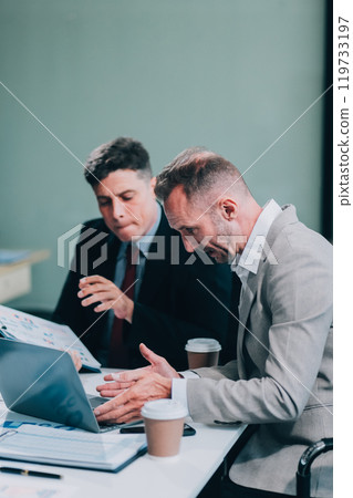 Two businessmen working together Analyze financial reports with charts and graphs while using the calculator to calculate budget, income, taxes, business growth. Startup business idea. 119733197