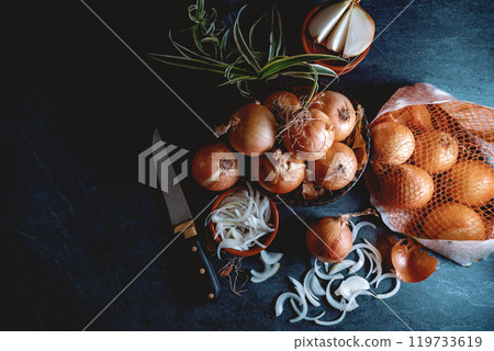 Brown onions and slices on wooden cutting board.Healthy food background. 119733619