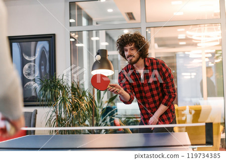 Business colleagues take a break from work to enjoy a game of table tennis, fostering teamwork and camaraderie in the workplace 119734385