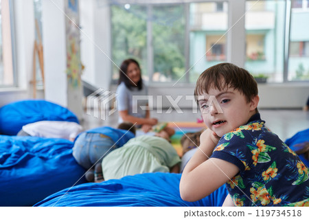 A happy female teacher sitting and playing hand games with a group of little schoolchildren 119734518