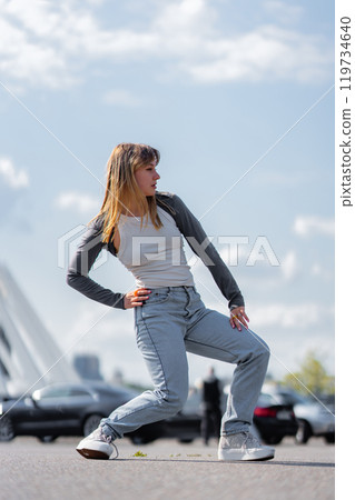Dancer performing dynamic pose outdoors under a bright sky 119734640