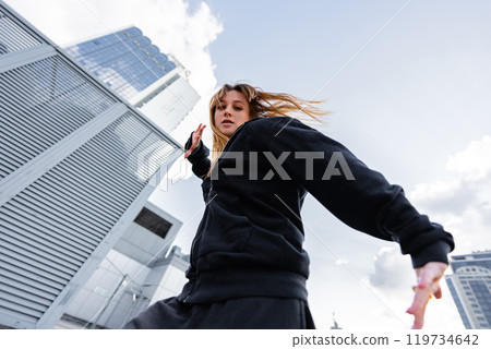 Dynamic urban dancer performing expressive movements on a city rooftop Dynamic urban dancer performing expressive movements on a city rooftop 119734642