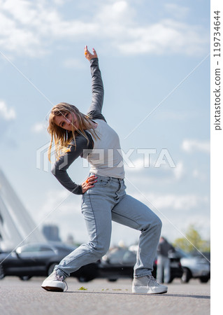 Dancer showcasing expressive moves under a bright sky in urban setting Dancer showcasing expressive moves under a bright sky in urban setting 119734644