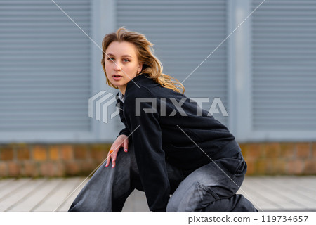 Young woman striking a dynamic pose in urban setting during the day Young woman striking a dynamic pose in urban setting during the day 119734657