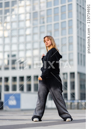 Young woman confidently posing in urban setting with modern architecture 119734691