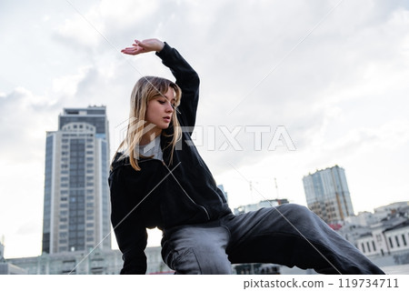 Young dancer performing a graceful movement on a rooftop in the city 119734711