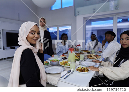 In the sacred month of Ramadan, a Muslim family joyously comes together around a table, eagerly awaiting the communal iftar, engaging in the preparation of a shared meal, and uniting in anticipation 119734720