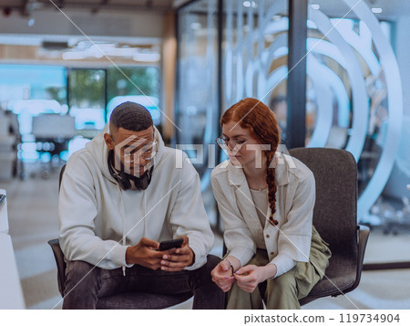 In a modern office African American young businessman and his businesswoman colleague, with her striking orange hair, engage in collaborative problem-solving sessions 119734904