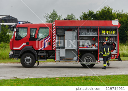 A firefighter meticulously prepares a modern firetruck for a mission to evacuate and respond to dangerous situations, showcasing the utmost dedication to safety and readiness in the face of a fire A firefighter meticulously prepares a modern firetruck for a mission to evacuate and respond to dangerous situations, showcasing the utmost dedication to safety and readiness in the face of a fire 119734931