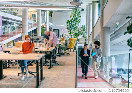 In a modern startup office, a diverse group of young professionals collaboratively tackles various business problems and challenges, surrounded by their engaged colleagues, fostering innovation and 119734963