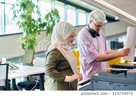 In a modern startup office, a business-minded Muslim woman wearing a hijab collaborates with her colleague, symbolizing diversity, empowerment, and success in the contemporary corporate world In a modern startup office, a business-minded Muslim woman wearing a hijab collaborates with her colleague, symbolizing diversity, empowerment, and success in the contemporary corporate world 119734970