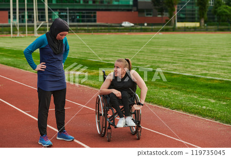 A Muslim woman wearing a burqa resting with a woman with disability after a hard training session on the marathon course A Muslim woman wearing a burqa resting with a woman with disability after a hard training session on the marathon course 119735045
