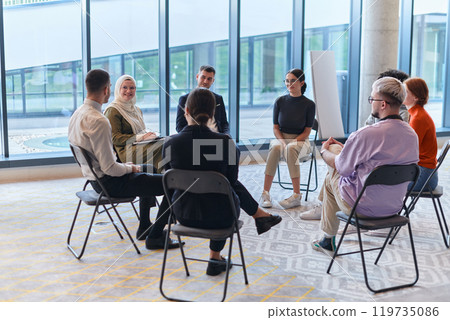 A diverse group of young business entrepreneurs gathered in a circle for a meeting, discussing corporate challenges and innovative solutions within the modern confines of a large corporation A diverse group of young business entrepreneurs gathered in a circle for a meeting, discussing corporate challenges and innovative solutions within the modern confines of a large corporation 119735086