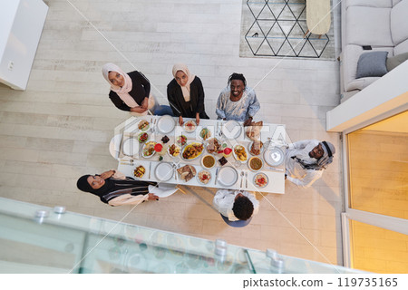 Top view of a Muslim family joyously comes together around a table, eagerly awaiting the communal iftar, engaging in the preparation of a shared meal, and uniting in anticipation of a collective Top view of a Muslim family joyously comes together around a table, eagerly awaiting the communal iftar, engaging in the preparation of a shared meal, and uniting in anticipation of a collective 119735165