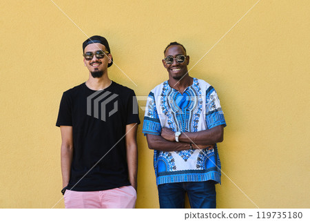 Two Male Friends: African American Teenager in Sudanese Traditional Attire Leaning Against Yellow Wall Two Male Friends: African American Teenager in Sudanese Traditional Attire Leaning Against Yellow Wall 119735180