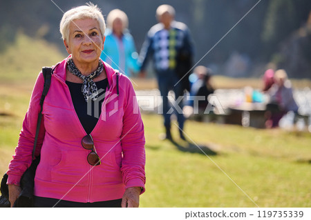 A senior woman finds serenity and wellness as she strolls through nature, illustrating the beauty of maintaining an active and health-conscious lifestyle in her golden years 119735339