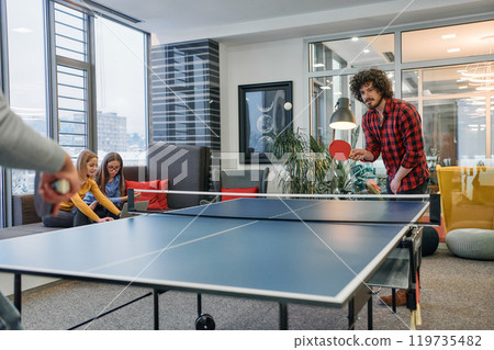 Business colleagues take a break from work to enjoy a game of table tennis, fostering teamwork and camaraderie in the workplace Business colleagues take a break from work to enjoy a game of table tennis, fostering teamwork and camaraderie in the workplace 119735482