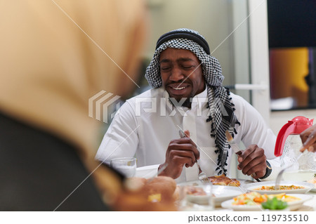A traditional and diverse Muslim family comes together to share a delicious iftar meal during the sacred month of Ramadan, embodying the essence of familial joy, cultural richness, and spiritual unity 119735510