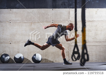 A muscular man captured in air as he jumps in a modern gym, showcasing his athleticism, power, and determination through a highintensity fitness routine A muscular man captured in air as he jumps in a modern gym, showcasing his athleticism, power, and determination through a highintensity fitness routine 119735518