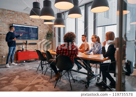 African-American businessman leads a meeting, passionately presenting a business plan to his attentive team, fostering collaboration and strategic thinking 119735578