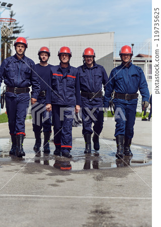 A team of confident and accomplished firefighters strides purposefully in their uniforms, exuding pride and satisfaction after successfully completing a challenging firefighting mission 119735625