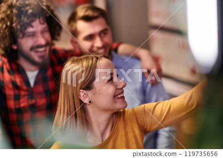 A diverse group of business professionals take a break from their tasks in a modern startup office to capture a creative selfie, showcasing teamwork and a vibrant workplace culture 119735656