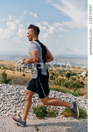 Determined Athlete Running Through Rugged Mountain Terrain at Sunrise. Determined Athlete Running Through Rugged Mountain Terrain at Sunrise. 119735697