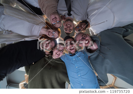 In a modern office, a group of young business professionals is captured in a warm and embracing hug, reflecting the spirit of unity, collaboration, and shared success in their dynamic workplace. In a modern office, a group of young business professionals is captured in a warm and embracing hug, reflecting the spirit of unity, collaboration, and shared success in their dynamic workplace. 119735720