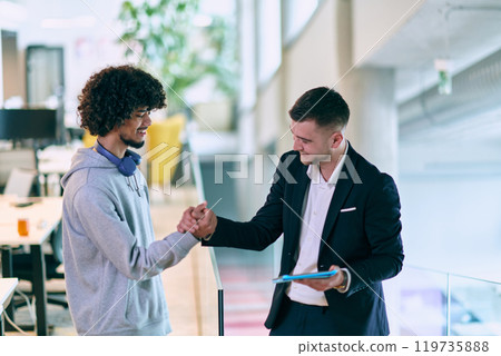 In a modern office setting, an African American businessman and his director confidently extend their hands in congratulations, symbolizing successful resolution of a business problem, amidst a 119735888