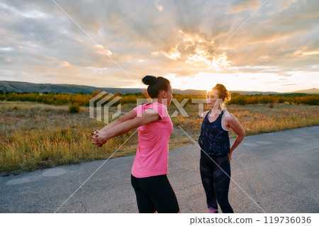Two Women Athletes Stretching at Sunset in Beautiful Natural Surroundings 119736036