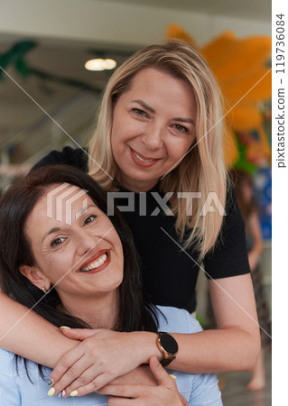 Two women share a heartfelt embrace while at a preschool, showcasing the nurturing and supportive environment for learning and growth 119736084