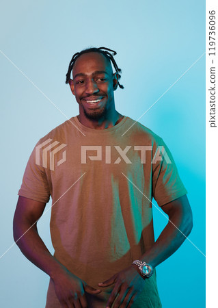 A confident and stylish African American man strikes a pose against a captivating blue gel background, showcasing his charismatic presence and contemporary fashion sense in a dynamic and vibrant 119736096