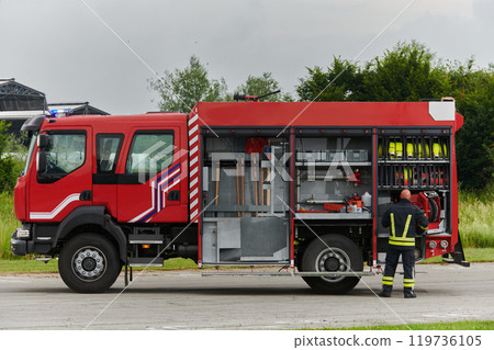 A firefighter meticulously prepares a modern firetruck for a mission to evacuate and respond to dangerous situations, showcasing the utmost dedication to safety and readiness in the face of a fire 119736105