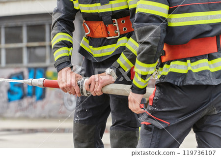 In a dynamic display of synchronized teamwork, firefighters hustle to carry, connect, and deploy firefighting hoses with precision, showcasing their intensive training and readiness for challenging In a dynamic display of synchronized teamwork, firefighters hustle to carry, connect, and deploy firefighting hoses with precision, showcasing their intensive training and readiness for challenging 119736107