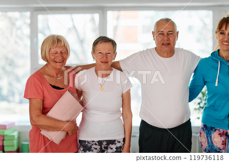 A group of seniors and one man happily pose with their yoga instructor after a successful training session. 119736118