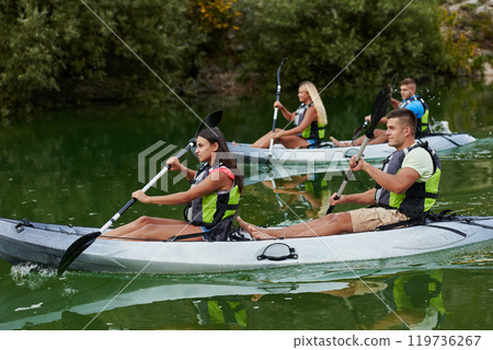 A group of friends enjoying having fun and kayaking while exploring the calm river, surrounding forest and large natural river canyons 119736267