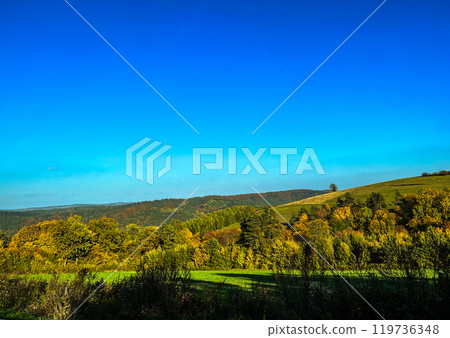 Asphalt road in the autumn forest with colourful trees and blue sky. View from the car. Asphalt road in the autumn forest with colourful trees and blue sky. View from the car. 119736348