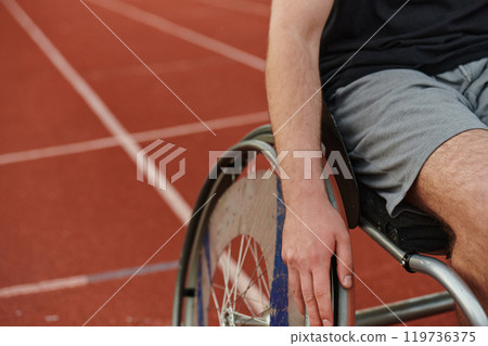 Close up photo of a person with disability in a wheelchair training tirelessly on the track in preparation for the Paralympic Games 119736375