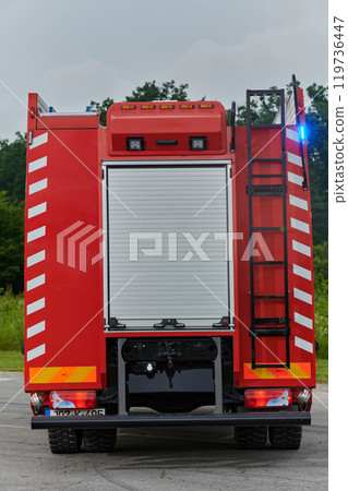 In this captivating scene, a state-of-the-art firetruck, equipped with advanced rescue technology, stands ready with its skilled firefighting team, prepared to intervene and respond rapidly to 119736447