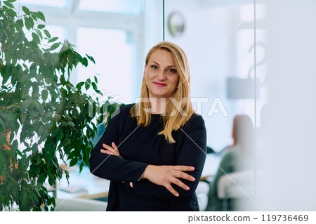 Brunette Businesswoman with Crossed Arms Standing in Front of Modern Office. Brunette Businesswoman with Crossed Arms Standing in Front of Modern Office. 119736469